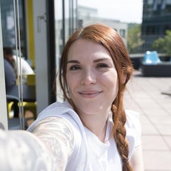 Female Trusted Shops employee smiles for a Selfie.