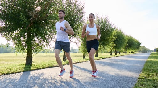 Two young people are jogging in a park.